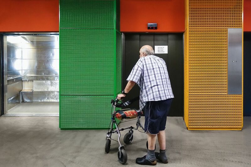 Old man in front of the hospital lift - a Photographic Art by Stefan Zausinger